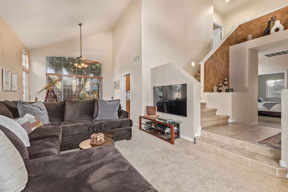 A spacious living area featuring a large sectional sofa, a TV unit, and a prominent window area, creating a cozy corner for relaxing or working. The space is versatile for streaming, remote work, or unwinding after a long day, with natural light enhancing the inviting atmosphere.