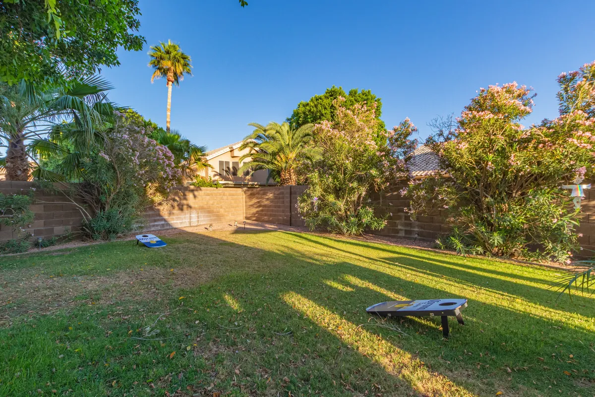 A lush outdoor area featuring abundant greenery, a dedicated outdoor game space, and vibrant flowering plants. The scene conveys a sense of playful relaxation, with ample room for guests or family to enjoy games and outdoor gatherings. The backyard’s open layout suggests flexibility for a variety of activities, including putting practice or group entertainment.