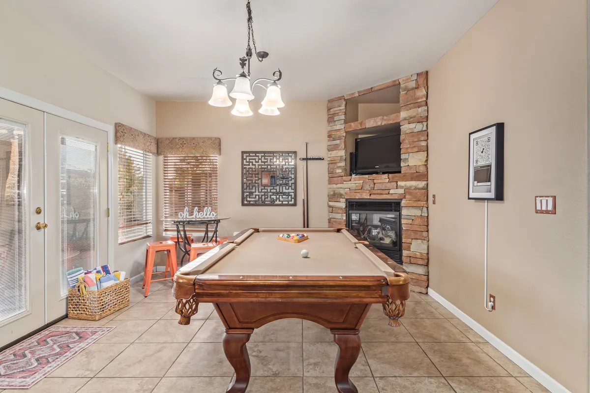 Inside, the vibrant game room is centered around a pool table, with a cozy fireplace, sophisticated chandelier, and striking wall art. The space invites friendly competitions, intimate conversations, and memorable indoor celebrations, embodying the spirit of social connection.