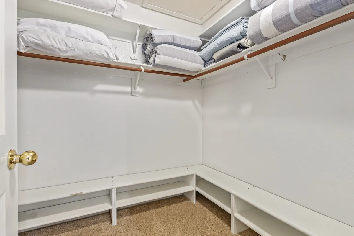 A tidy interior space with bright white walls, neatly stacked linens on open shelves, and an uncluttered floor area. The room exudes a sense of orderliness and calm, promoting comfort and ease of organization for longer stays.