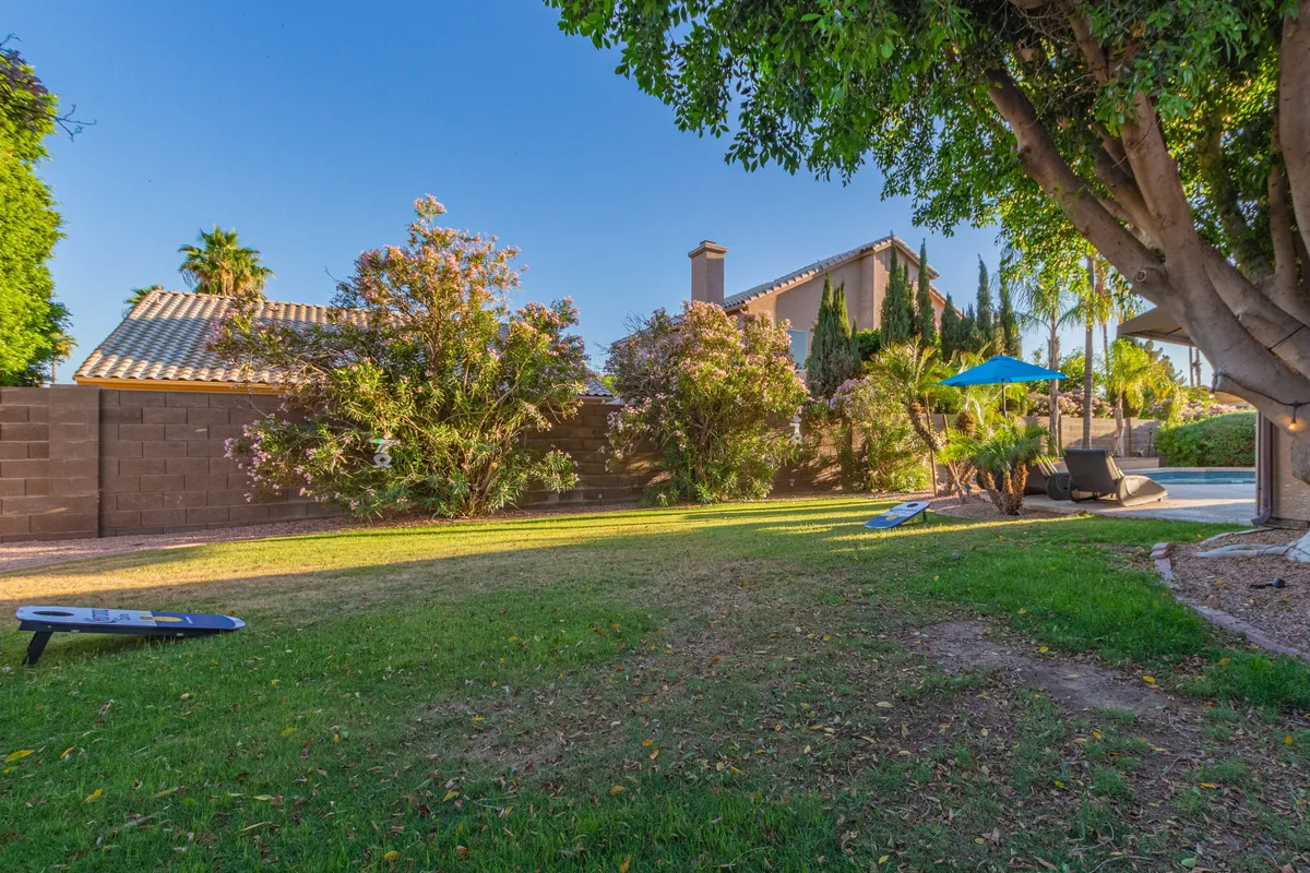 A tranquil pool area surrounded by lush greenery with comfortable patio furniture and a sunshade umbrella, offering a relaxing oasis ideal for breaks or unwinding after work. The setting emphasizes both privacy and open-air serenity.